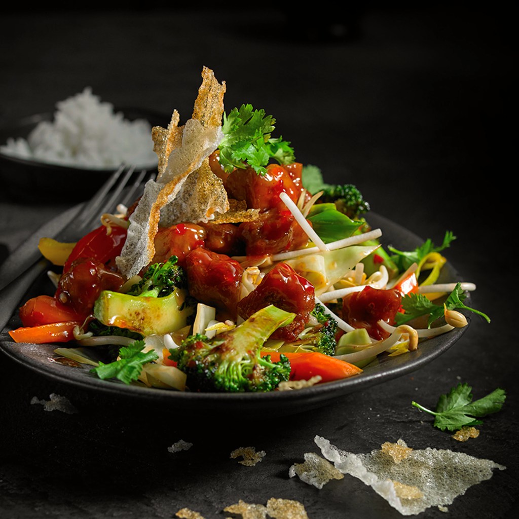 Frisch zubereitete Asia Knoblauch Wok Sensation mit gebratenem Gemüse, würziger Knoblauchsauce und asiatischem Topping in einer Schüssel serviert.